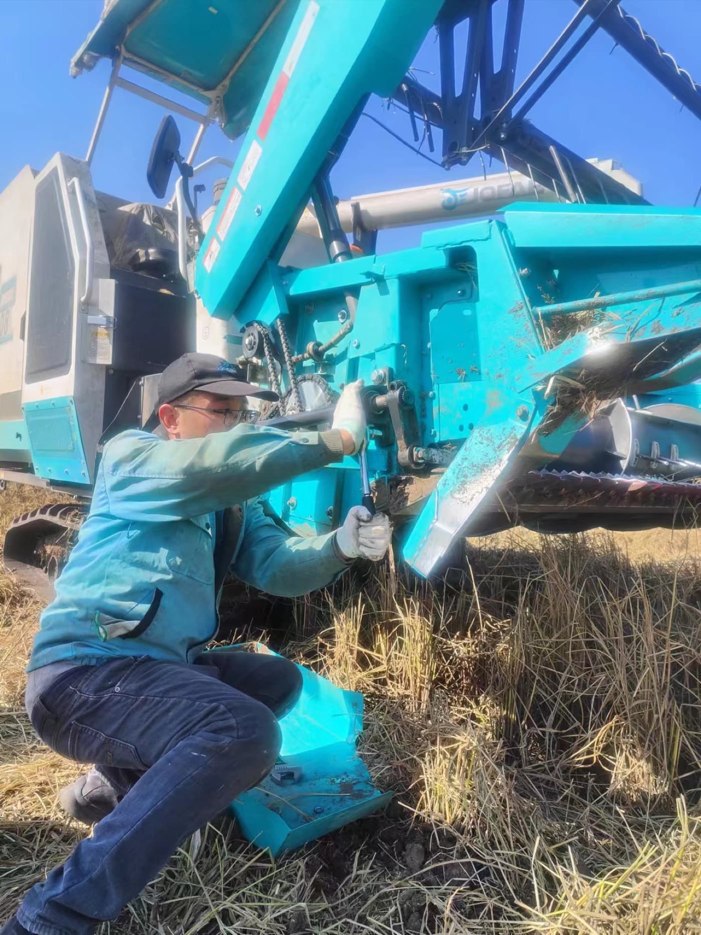 JOFAE technician servicing a combine harvester in the field